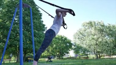 Genç kadın fitness trx parkta şınav yapma. 4 k yavaş mo görüntüleri aşağıdaki