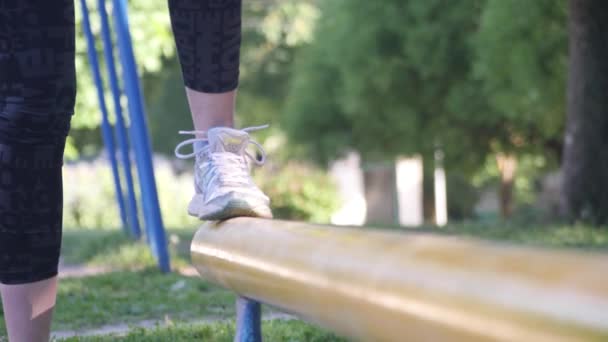 Fötter i sneakers kvinnliga idrottare som startar utbildning på balans i sommaren park. 4 k långsamma mo — Stockvideo