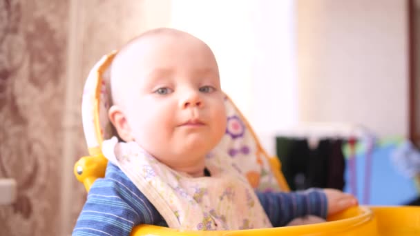 Pequeno bebê bonito olhando para a câmera enquanto as mães mão alimentá-lo com uma colher na cadeira alta 4K slow mo — Vídeo de Stock
