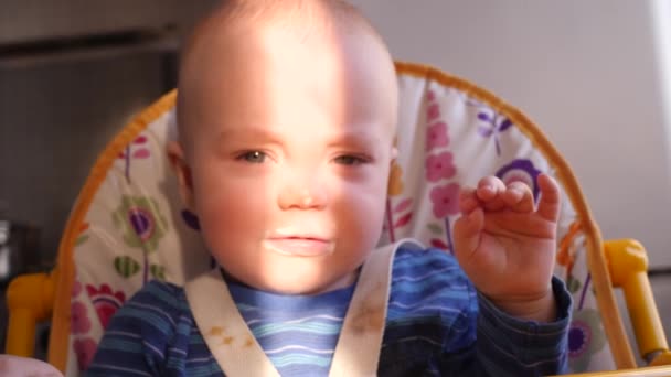 Pequeño retrato de bebé carismático que mira a la cámara y luego estornuda en un rayo de luz solar en su cara 4K lento mo — Vídeos de Stock