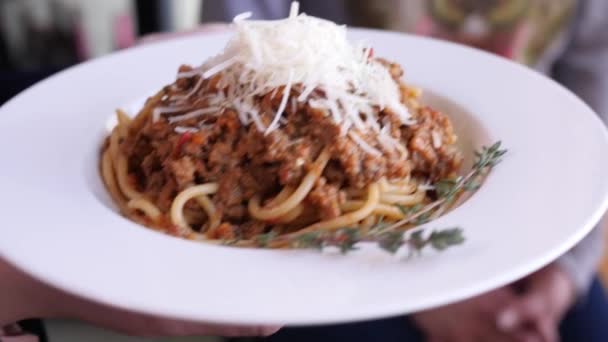 Kadın elleri parmesan peynirli bolonez makarna tabağını ahşap masaya koyuyor. — Stok video