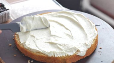 Bir pasta pişirme çilek ile doldurulmuş. Bir krem pişmiş hamur üzerinde yayılan kadın.