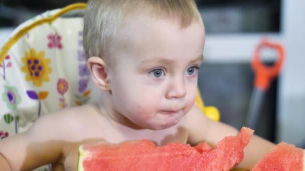 Kleine schöne Baby-Junge isst ein Stück Wassermelone am Kindertisch Nahaufnahme Slow-mo-Video in 4k — Stockvideo
