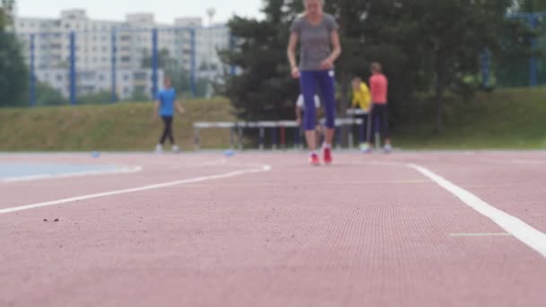 Jovem bela menina atleta treinamento correndo rápido começar no estádio de atletismo da cidade durante um dia de treinamento em câmera 4K câmera lenta — Vídeo de Stock