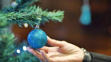 Noel ağacına top asan kadın eller. Kış tatili Noel ve Yeni Yıl Dekorasyonu. Yanıp sönen Garland. Noel ağacı ışıkları parıldıyor.