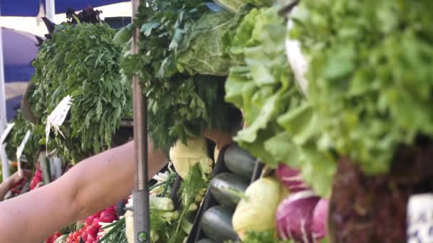 Mostrador con vegetación y verduras en el mercado de la ciudad en el día de verano y un hombre borroso irreconocible tomando una bolsa con verduras en el fondo, de cerca ver video en cámara lenta en 4K — Vídeos de Stock