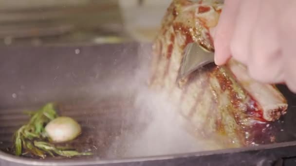 Onherkenbaar man koks handen met twee vorken zijn rotaring een sappige rundvlees biefstuk wich roosteren met rozemarijn en knoflook op een hete zwarte grill pan, close-up weergave slow motion video in 4k — Stockvideo