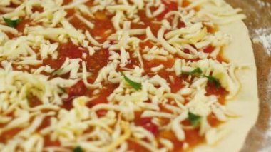 Pizza pişiriyorum. Şef, domates ezmesiyle yağlanmış pizzanın tabanına peynir ve fesleğen koydu. Bir erkek ya da kadın ev işleriyle meşgul. Lezzetli bir pizza hazırlıyorlar.