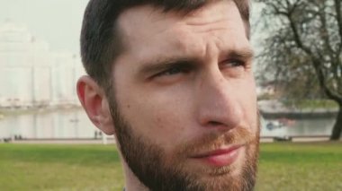 etrafında görünümlü ve daha sonra yaz şehir arka plan yavaş hareket kamera içine yanıp söner sakallı genç adam 4k portre video yakın