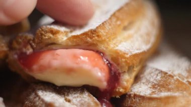 kadın parmak yeni ev yapımı Eclairs üzerinde 4k yavaş hareket kırmızı ve beyaz muhallebi ile toz şeker serpilir basmak video yakın