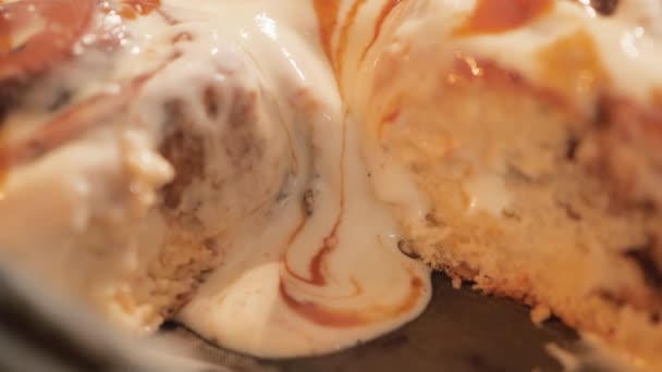 Crema de caramelo cremosa blanca fluye hacia abajo de bollos de canela calientes frescos en cámara lenta de cerca vídeo 4K. — Vídeo de stock