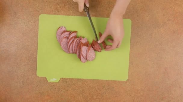 L'uomo o la donna su un tagliere viene tagliato a fette di salame. . — Video Stock