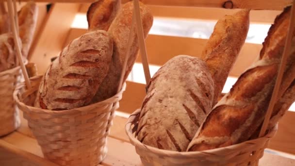 Pains et autres produits de boulangerie dans des paniers décoratifs sur des étagères de boulangerie en bois en arrière-plan tir moyen au ralenti en 4K — Video