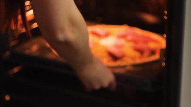 Kadın veya adam pişirme için fırın pizza koymak.