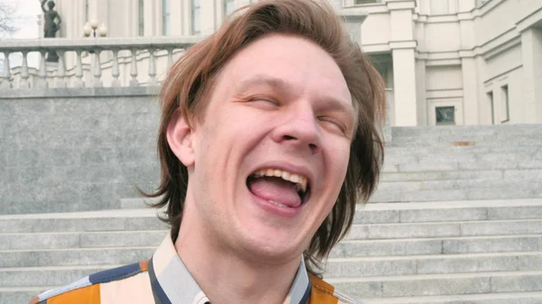 Charismatic middle-aged man looking at the camera on city architecture background, grimacing and laughing slow motion close up video in 4K — Stock Photo, Image