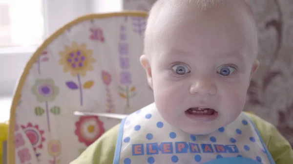 Mooie baby jongen aan de tafel nemen een koekje in zijn hand, eten, kijken in de camera en babbelen close-up bekijken slow mo video in 4K — Stockfoto