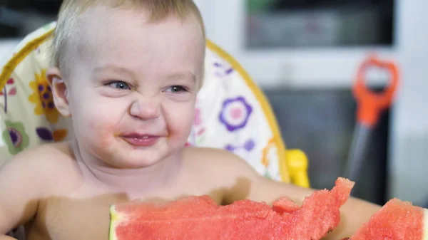 Mooie kleine jongen het eten van een watermeloen aan de kinderen tafel en schudden zijn hoofd gelukkig glimlachen close-up te bekijken slow mo video in 4k — Stockfoto