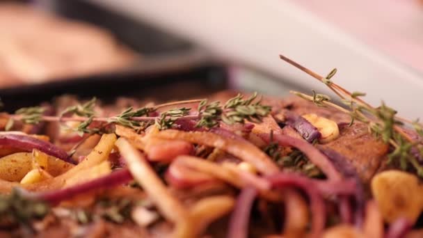 Rohes Rinderfilet, mariniert mit Zwiebeln, Knoblauch und Rosmarin, liegt in Zeitlupe in einem schwarzen Tablett im Regal. — Stockvideo