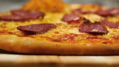 Taze yapılmış sıcak iştah açıcı peperoni pizza arka planda erkek veya kadın şef bulanık bir rakam tarafından ahşap bir masa üzerinde bırakır yavaş hareket yakın ön görünüm 4k video