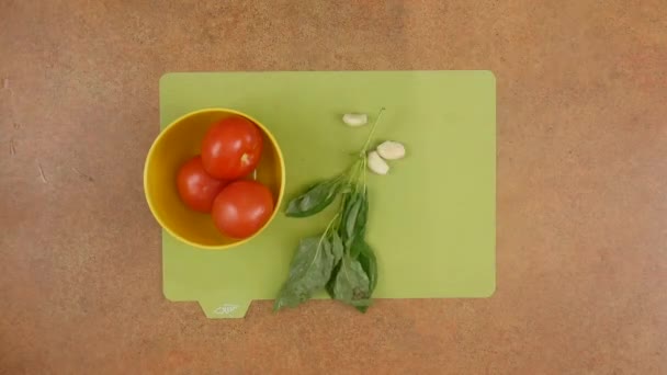 Uma mulher chefs mãos mistura tomates, verduras de manjericão, sal e pimenta fazendo um molho para pizza de peperoni com queijo em uma mesa marrom na vista superior lapso de tempo 4K vídeo — Vídeo de Stock