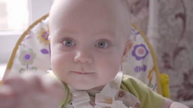 çocuklar masada oturan, kameraya izlemek ve sonra bunun için ulaşan güzel yürümeye başlayan çocuk yakın görünüm yavaş mo 4 k'dan fazla video çekim