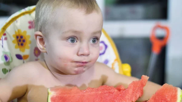 Kleine mooie babyjongen een stukje watermeloen te eten aan de tafel van de kinderen close-up weergave langzame mo video in 4k — Stockfoto