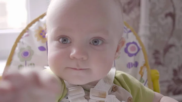 Beau tout-petit garçon assis à la table des enfants, regarder dans la caméra, puis atteindre pour elle vue de près ralenti mo vidéo en 4K — Photo