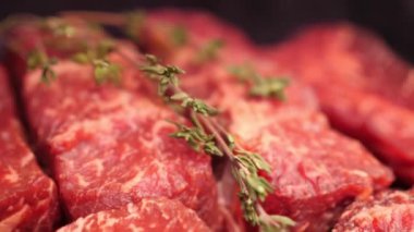 Biberiyeli taze çiğ mermer et filetosu yavaş çekim 4K video 'da satışa sunulmak üzere siyah tepside duruyor.