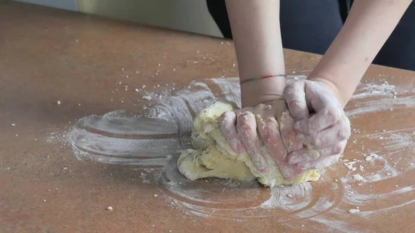 Женские руки месят тесто в муке на столе — стоковое фото