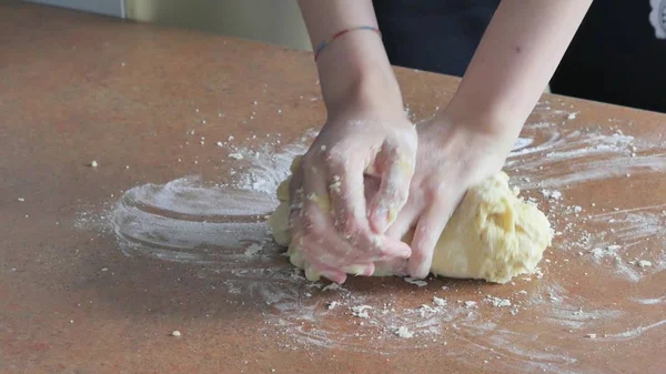 Женские руки месят тесто в муке на столе — стоковое фото