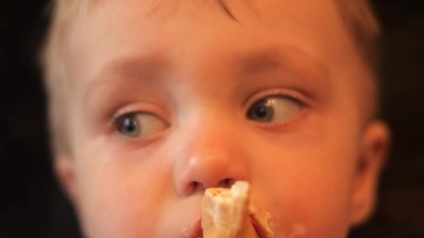 Um menino adorável comendo a xícara de waffle de sorvete de baunilha e a criança olha para a câmera e ao redor de si mesmo em câmera lenta retrato close up vídeo 4K . — Vídeo de Stock