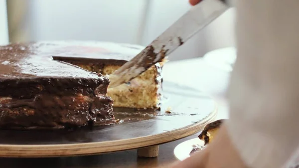 Meisje snijdt een stuk van chocolade taart, en zet het op een close-up shot van de plaat — Stockfoto