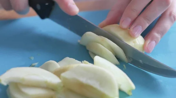 Молодая женщина режет яблоко на кухне — стоковое фото