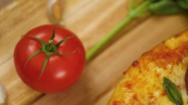 sıcak peperoni pizza fesleğen yeşillik, domates ve sarımsak yavaş hareket yakın üst görünüm 4k video arka planda hiçbir erkek veya kadın ile dekore edilmiş ahşap bir tabak üzerinde yatan.