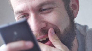 Genç sakallı bir adam cep telefonunu kullanır. Yakın çekim, gözlere odaklan..