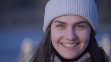 Genç ve güzel bir kadın portresi. Yeşil gözlü esmer bir kız. Kameraya bakıp arka planda bir gölle uzaklaşıyor..