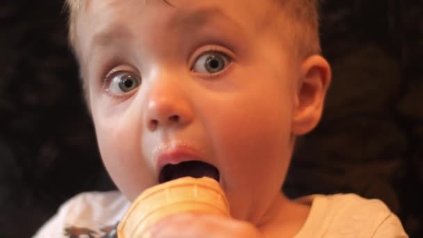 Retrato de un niño pequeño que lamiendo helado de vainilla blanco en una taza de waffle, ensucia su cara con helado y luego se limpia la boca con una servilleta en cámara lenta de cerca 4K video . — Vídeos de Stock