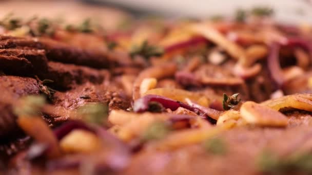 Pieces tenderloin of raw beef meat covered and marinated with sliced onion, garlic and rosemary are lying ready for sale in the store refrigerator in slow mo camera motion 4K video with no people — Stock Video