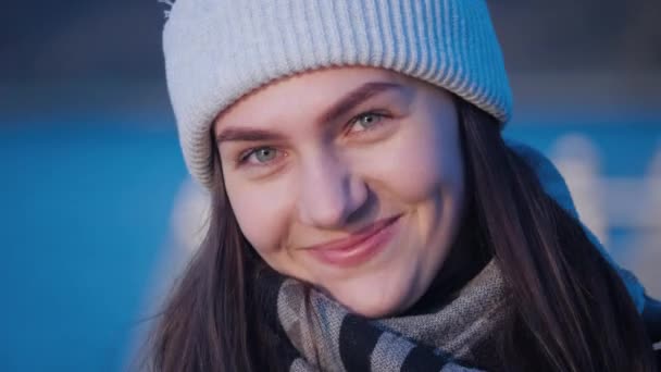 若いです美しいです緑の目のブルネットの女の子の肖像画誰が笑って、カメラを見て、離れて近くに都市公園の湖の背景に4kビデオ. — ストック動画