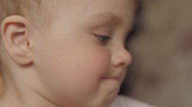 onun önünde bakıyor ve daha sonra yavaş çekim 4k video kameraya bakar başını döner sevimli bir bebek bebek yan görünümü yakın çekim portre.