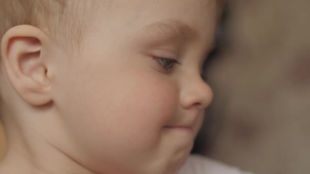 Seitenansicht Nahaufnahme Porträt eines entzückenden kleinen Jungen, der vor sich hinschaut und dann seinen Kopf dreht, schaut in Zeitlupe in die Kamera 4k Video. — Stockvideo