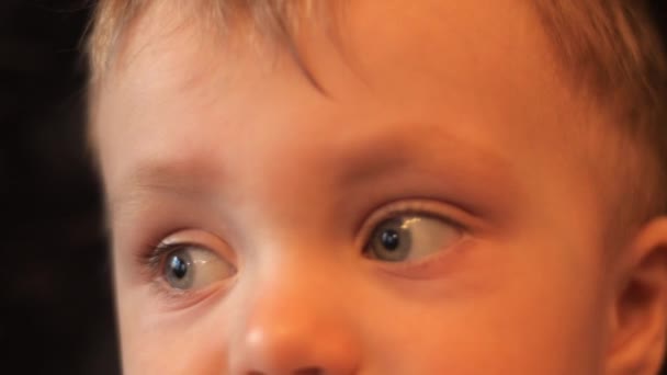 슬로우 모션 4K 배경 비디오에서 카메라와 주변을 바라보는 사랑스러운 아기 소년의 눈 클로즈업 초상화. — 비디오