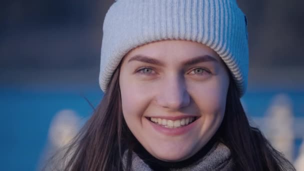 Jeune attrayant portrait de femme aux yeux verts qui regarde la caméra, souriant heureux et clignote avec un lac dans le centre-ville en arrière-plan en gros plan vidéo 4K . — Video