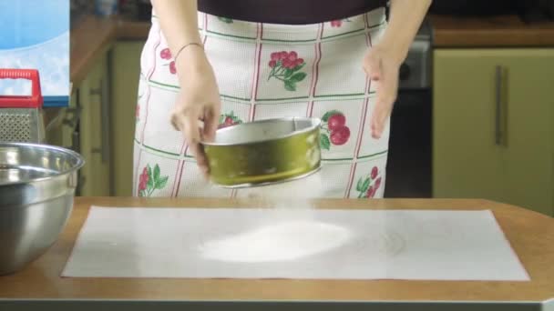 Jonge mooie vrouw op de tafel weegt de bloem met behulp van keukenweegschalen, kom en zeef voor dit. Close-up bekeken 3840 2160 uhd. — Stockvideo