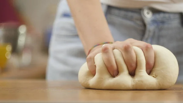 Mujer en la mesa de la cocina hace pizza de comida doméstica, manos de trabajo y empujando agitar amasar la masa, enfoque selectivo dolly shot —  Fotos de Stock