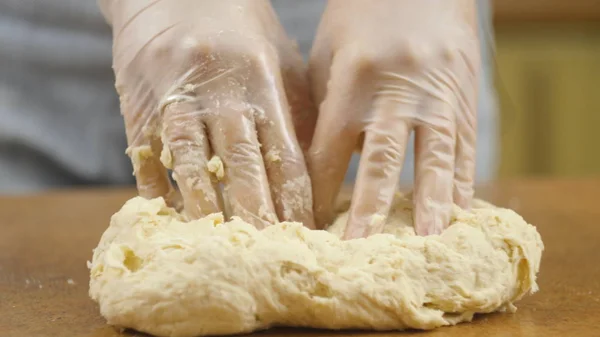 Femme mère ou fille sur la table de cuisine fait pizza alimentaire domestique, les mains travaillent et poussent pétrir pétrir la pâte, mise au point sélective dolly shot — Photo