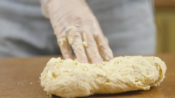 Femme mère ou fille sur la table de cuisine fait pizza alimentaire domestique, les mains travaillent et poussent pétrir pétrir la pâte, mise au point sélective dolly shot — Photo