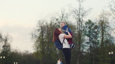 Mutlu ve neşeli anne, küçük oğlum parkta yürüyor. Annem oğlunu fırlatıyor.