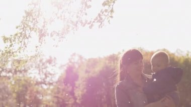 Genç anne kucağında güneşte parkta bir bebek tutar