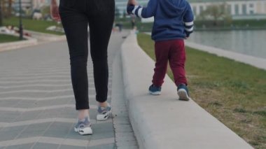 Anne, bebeğin elini tutuyor. Anne ve oğlu gezinti güvertesinde yürüyorlar..